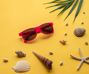 Obraz premium Tropical background with palm tree leaves, sunglasses, starfish and seashell on yellow background. Travel concept