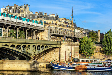 View of the Pont de Bir-Hakeim from the Ile aux Cygnes. Sailboat and buildings of Paris are visible in the background. Paris, France - 436529044