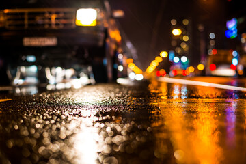 Rainy night in the big city, stream of cars traveling along the avenue. View from the level of asphalt