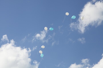 A many Helium balloons flying into the blue sky with white clouds at Sunny summer day