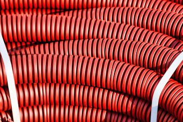 Red plastic corrugated hose for insulation and laying of wires and cable close-up. Background for an electrical component supplier with copy space