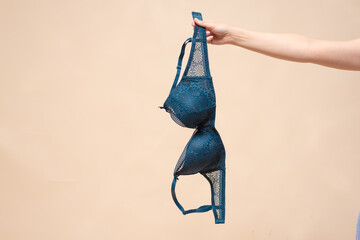 Woman is showing a new bra in the hand. Choosing a new bra concept. - obrazy, fototapety, plakaty