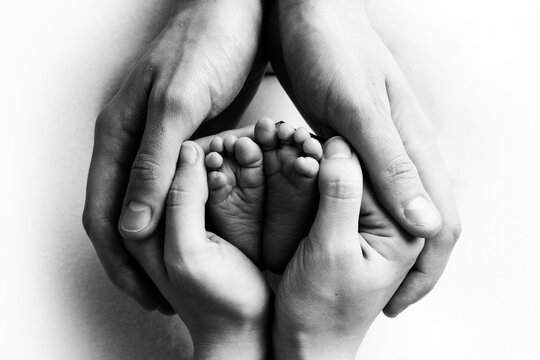 Tiny feet of a newborn child in the hands of a parent. One week old baby. The image of the first days of life. Concept image of happy family, motherhood and happy childhood.