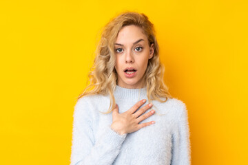 Young blonde woman isolated on yellow background surprised and shocked while looking right