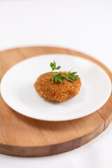 Pork cutlet garnished with parsley on a white plate