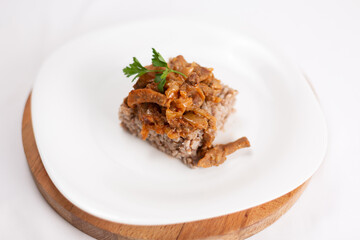 dish of buckwheat porridge with meat close-up on white background
