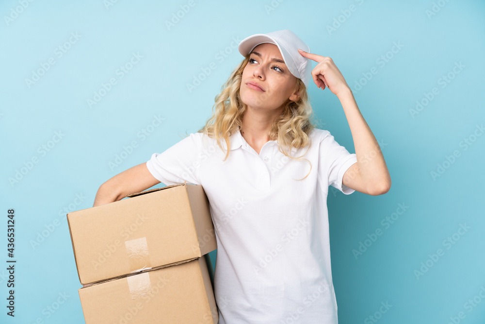 Canvas Prints Young delivery woman isolated on blue background having doubts and with confuse face expression