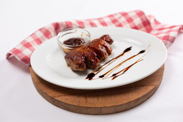Grilled meat with barbecue sauce on white plate
