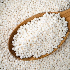 raw sabudana (tapioca sago) in wood spoon closeup