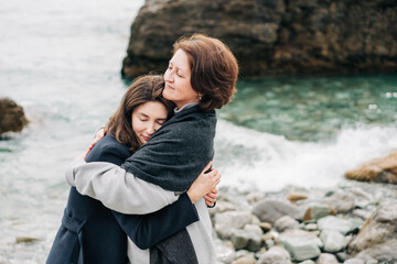 Two generations women embracing at the sea.