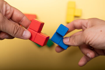 Hand holding piece of wooden block puzzle. wood cube stacking. Concept of complex and smart logical thinking. Slightly defocused and close up shot. on ... Mehr anzeigen.