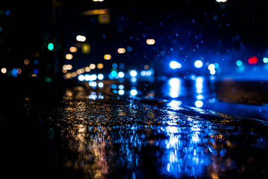 Rainy night in the big city, the cars rides on the road. The view from the sidewalk level © Georgii Shipin