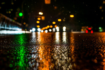 Rainy night in the big city, approaching headlights of cars traveling along the avenue. View from...