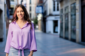 Fototapeta premium beautiful hispanic independent young woman lifestyle urban portrait. Lavender streetwear stylish looking at camera. Real people