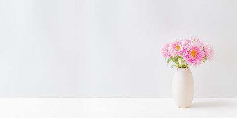 Fototapeta premium Pink flowers in a vase on a light background at home interior. Modern interior design