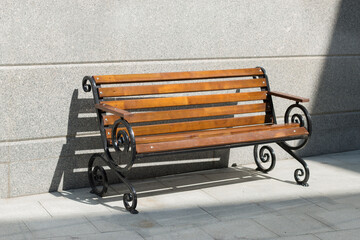 Empty wooden bench among concrete in the sunny day. Light and shadow