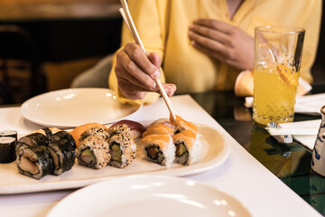 Sushi Japanese food close-up with woman hand in a restaurant. Lifestyle sashimi tasty seafood and...