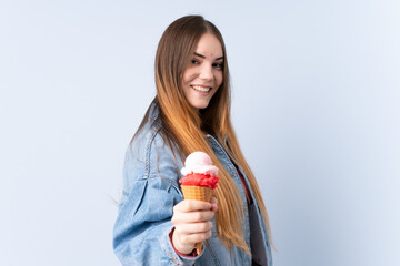 Young woman with a cornet ice cream isolated on blue background with happy expression