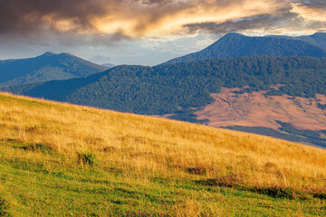 rural landscape with fields on hills. mountainous nature scenery in summertime at sunrise. glowing clouds above the ridge in the distance