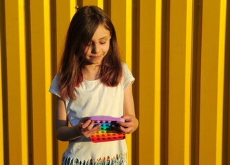Girl holding a toy pop it. Anti stress hand toy. Push pop fidget toy. - obrazy, fototapety, plakaty