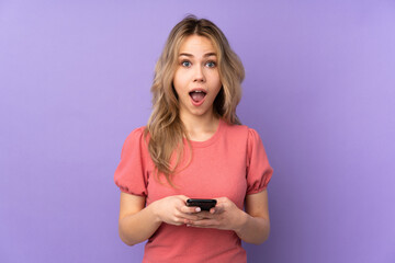 Teenager Russian girl isolated on purple background surprised and sending a message