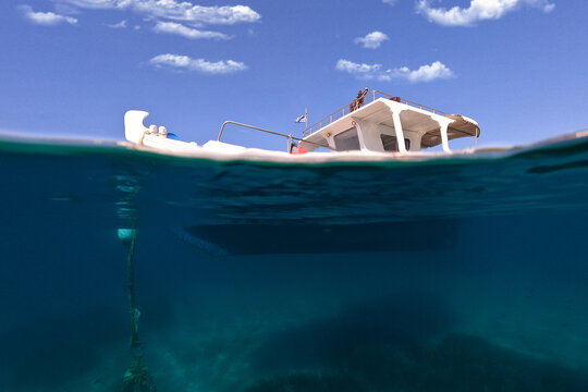 Underwater split photo of traditional fishing boat anchored in crystal clear sea of Schoinousa island, Cyclades, Greece