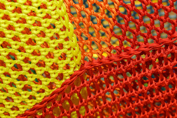 A rope net with a blurred background on the playground. Yellow, orange, and red grid colors