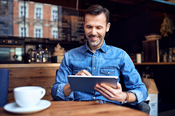 Happy man using digital tablet in a cafe