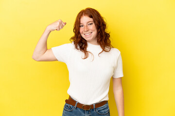 Teenager reddish woman isolated on yellow background doing strong gesture