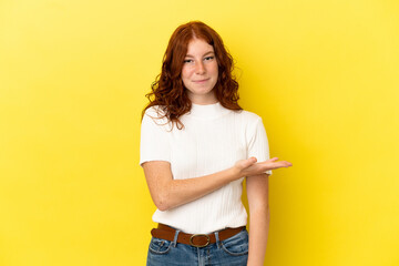 Teenager reddish woman isolated on yellow background presenting an idea while looking smiling towards
