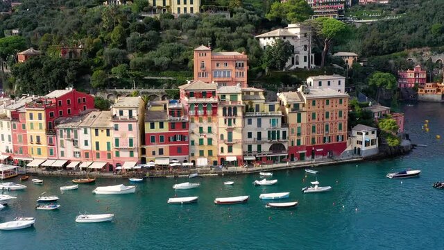 Aerial view of the harbor of Portofino in Italy. We can see boats and colorful houses in front of the mountain 4K