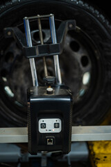 Close-up of a tire clamped by a leveler that passes the automatic alignment of the wheels in the garage, garage and tools for the mechanic.