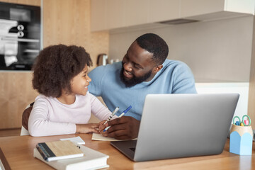 Happy african american family doing home task. Caring father help little daughter with school subject homework. Homeschooling conducted by parent, distant e-study and e-learning concept