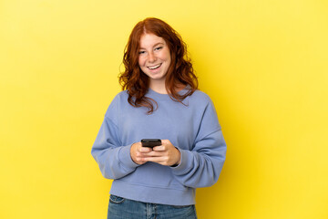 Teenager reddish woman isolated on yellow background surprised and sending a message