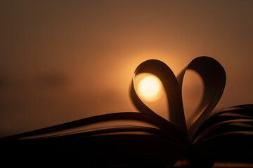 Open book with heart-shaped pages against a beautiful sunset