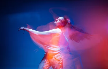 Fototapeten Dancing young mixed race girl enjoying moving in colorful neon studio light. Long exposure. Ethnic fiery dance © Georgii