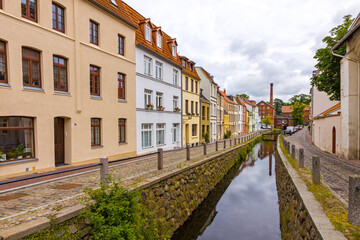 Fototapeta na wymiar Wismar old town. Colorful houses along the canal of Grube river, Wismar city, Mecklenburg-Vorpommern state, Germany. Cloudy summer day