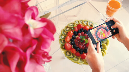 Woman taking a photo of fruits plate on smartphone
