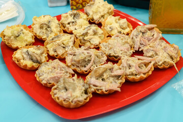 tartlets with a snack in a red plate on a festive table