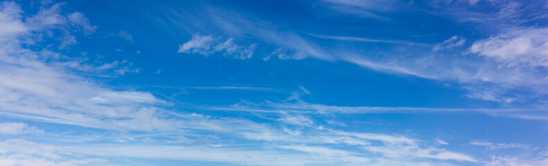 Naklejka na ściany i meble Panorama of blue sky with blurred white clouds. Abstraction of a cloudless clear sky.