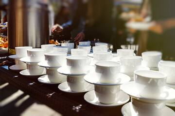 Thermos with hot water and many white cups for morning tea. Outdoor catering
