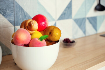 A large bowl of fruits and vegetables stands on the kitchen table