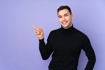 Young caucasian handsome man with turtleneck sweater isolated on purple background pointing finger to the side