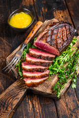 Sliced grilled duck meat breast fillet steak. Dark wooden background. Top view