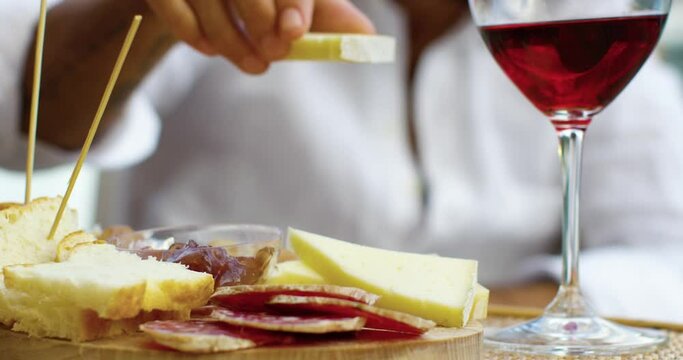Close up of a man taking and eating french cheese, near a glasse of red wine. He wears a white shirt - Red Camera 4K