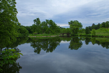 Fototapeta na wymiar Lyman Lakes in Northfield, Minnesota with lush green vegetation and reflection of blue sky on water 
