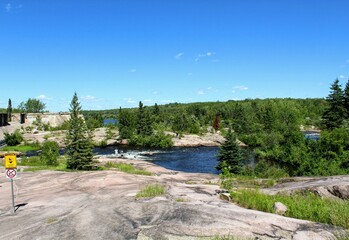 Fototapeta premium Pinawa Dam: Panoramic view of the river, stone bank and forest