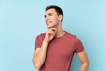 Young caucasian handsome man isolated on blue background thinking an idea while looking up