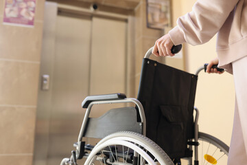 Woman rolls wheelchair to the elevator to meet disabled person
