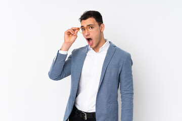 Young handsome businessman on isolated background with glasses and surprised